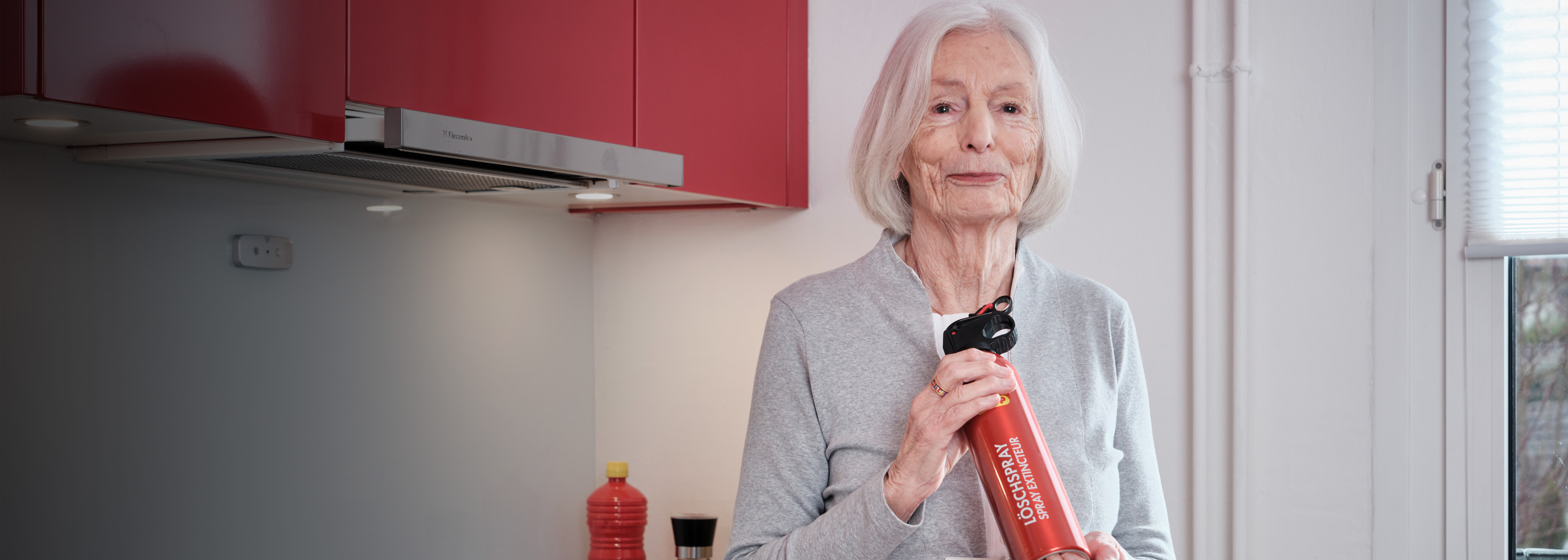 Signora anziana con uno spray estinguente in cucina